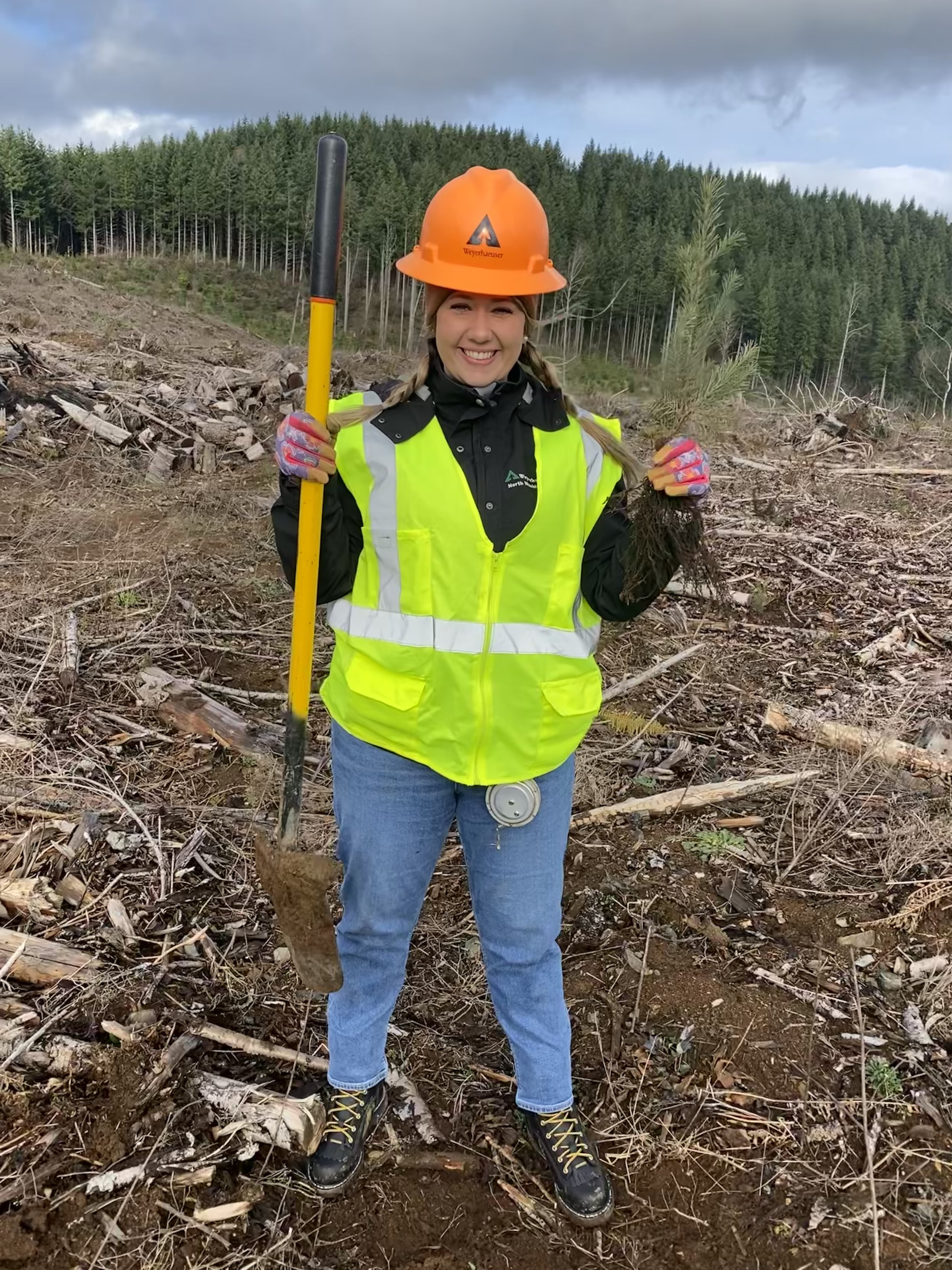 Image of Rachael holding up the first tree she ever dug up, on a field visit in Longview, Washington.