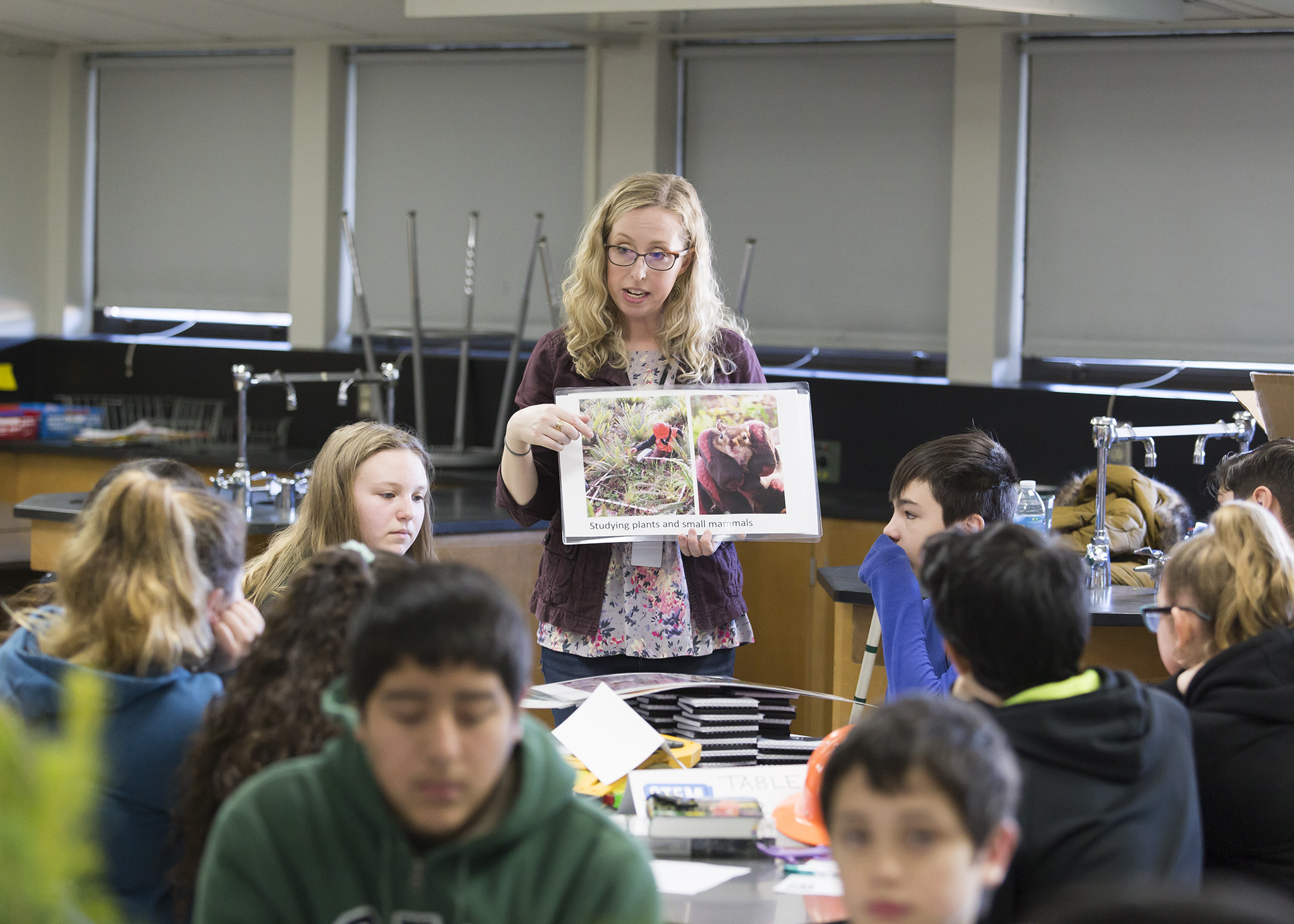 Image of Laura Six making a Project Learning Tree presentation to a high school class a few years ago. Laura stands among a group of students holding slides demonstrating the impact of careers in rural communities.